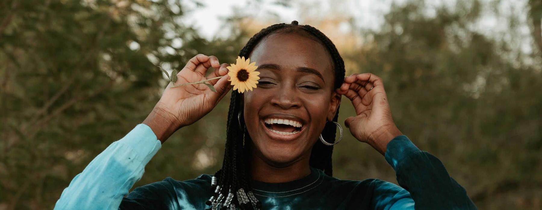 woman holds a flower in her hair in a park